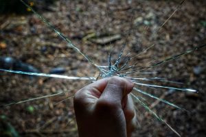 Photograph of fist breaking glass. Photo by Robert Anasch on Unsplash