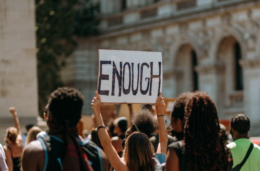 Person holding a sign reading Enough. Photo by Liam Edwards on Unsplash